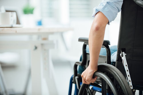 child using a wheelchair to move towards a kitchen table