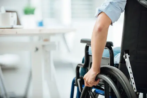 child using a wheelchair to move towards a kitchen table