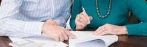 two people signing Powers of Attorney documents at a table
