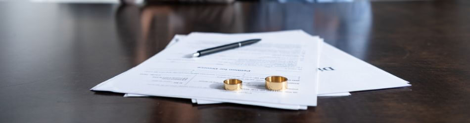 divorce paperwork with wedding rings on top
