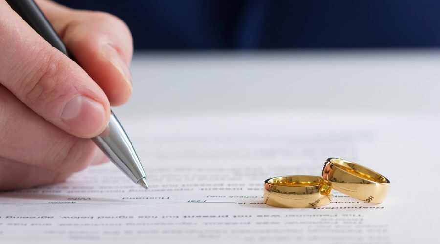 signing divorce decree next to rings