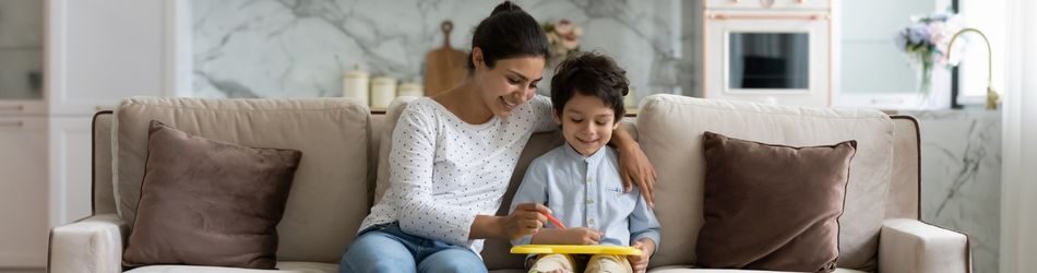 mother and son sitting down on a couch writing