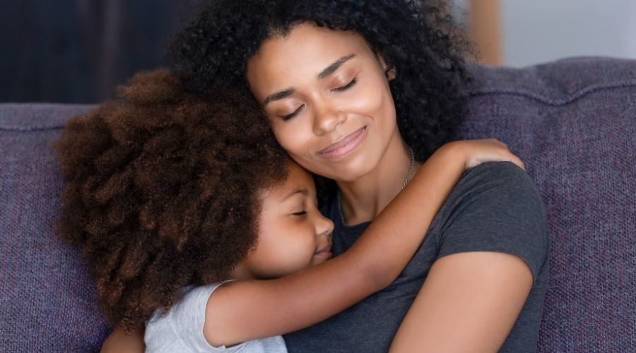 Mother hugging her daughter while smiling