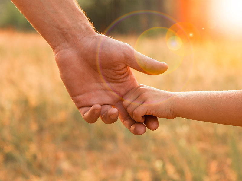 Dad holding hands with his son in a field