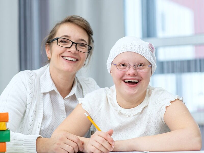 Mother and her special needs daughter writing together