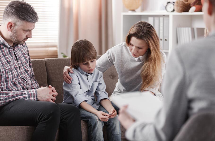 a mother and father sitting on a couch with their son 