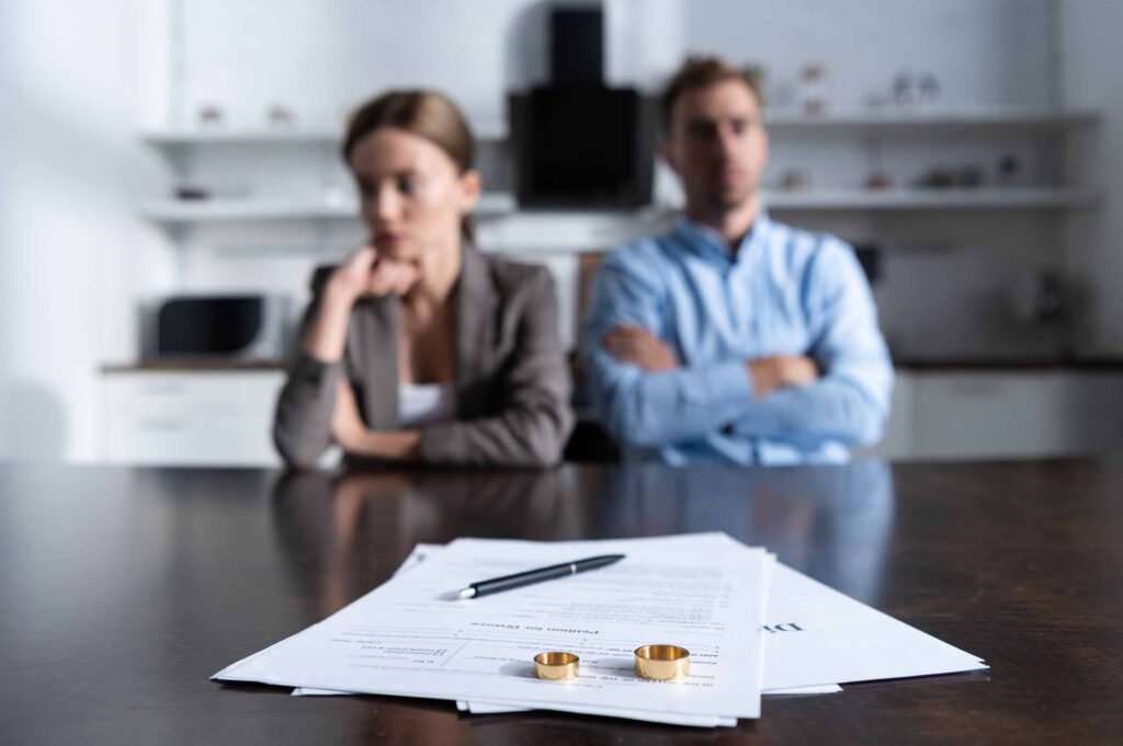 husband and wife looking upset at paperwork with wedding rings on top of it