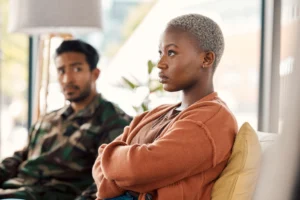 A Tampa couple discusses separation: a woman in the foreground stares angrily ahead with her arms crossed while the man in the background looks at her.