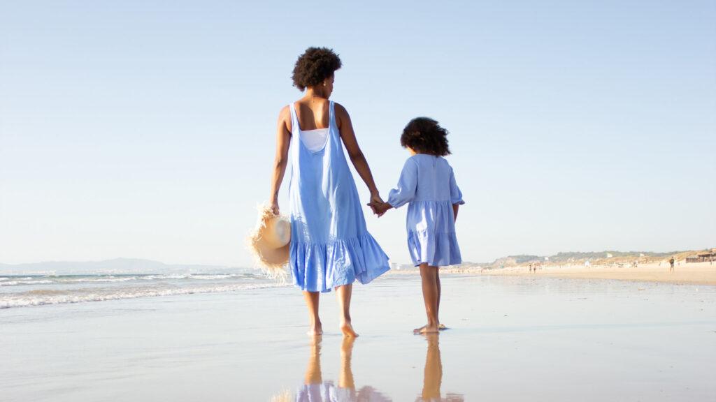 Single parent walking on the beach with her child