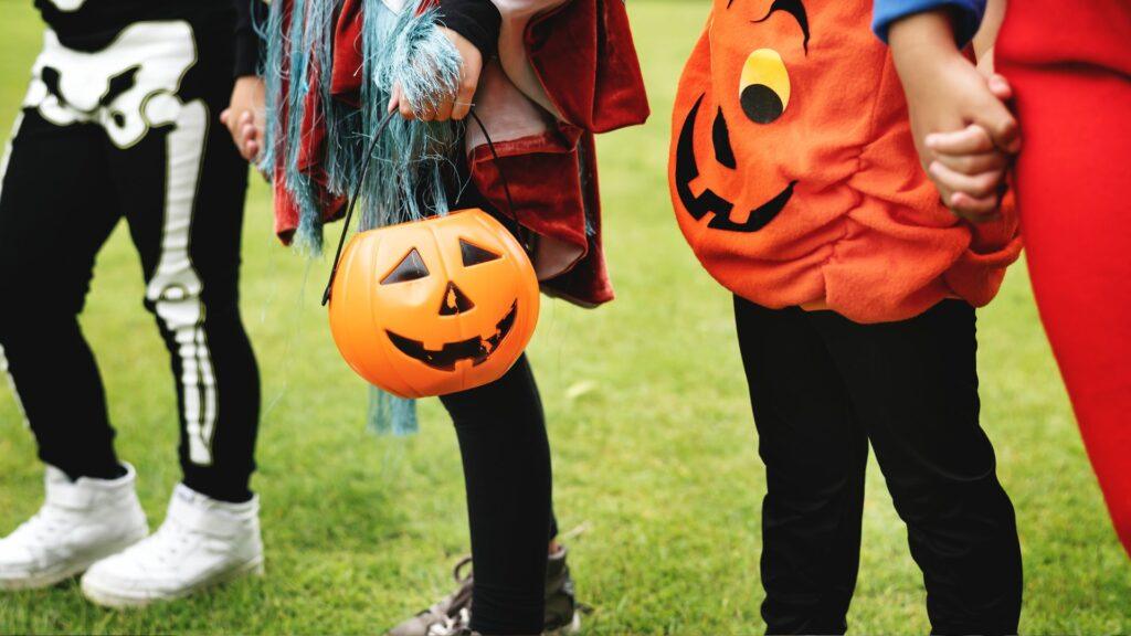 Children on a lawn, dress in Halloween costumes